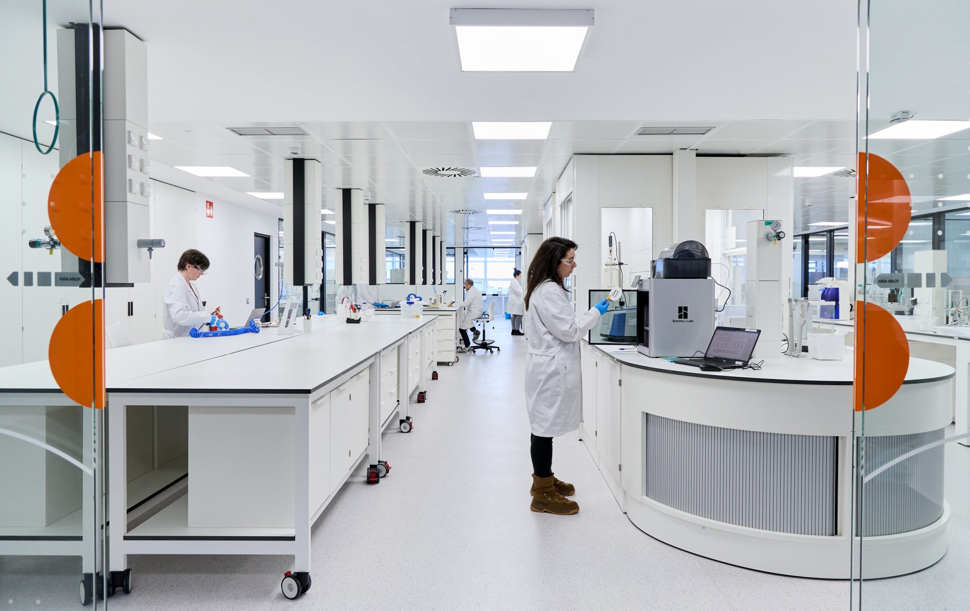 imagen de una mujer en un laboratorio de tecnalia, con las puertas abiertas y trabajadores.